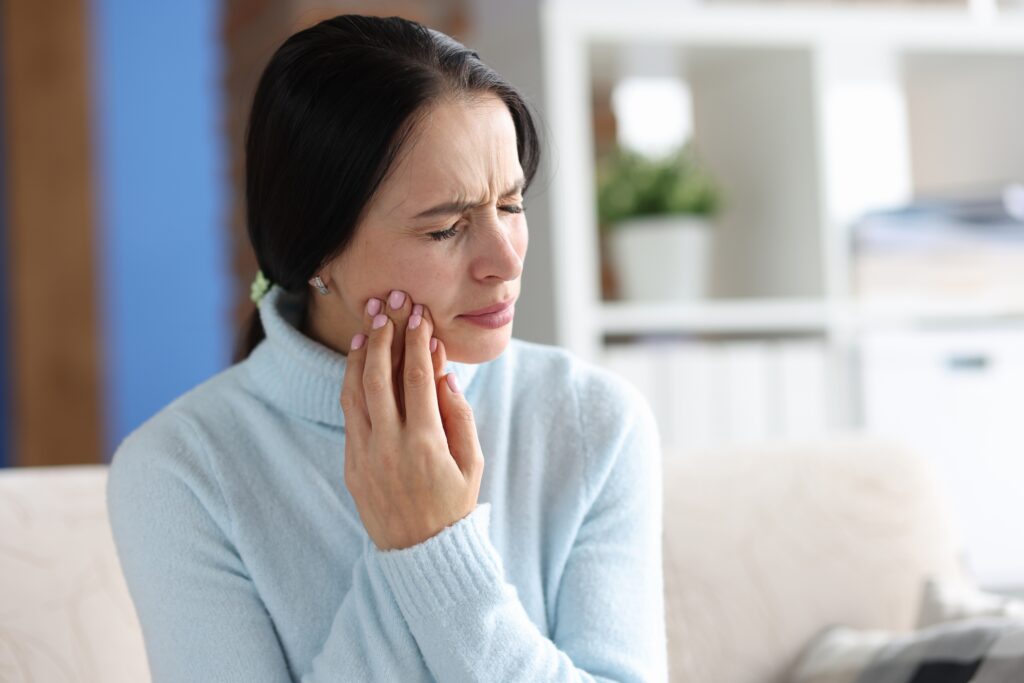 young woman suffering from severe tooth pain, possible dental emergency 