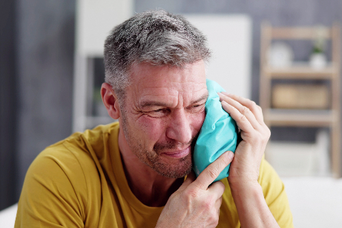 man with severe tooth pain holding an ice pack on his jaw