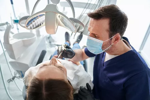 doctor wearing a blue mask examining a patients tooth injury
