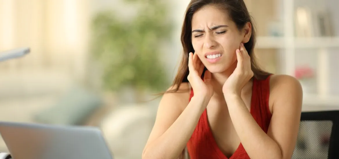 woman suffering from severe tooth and jaw pain, hands on jaw