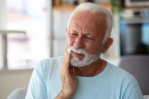 older man holding jaw in severe pain