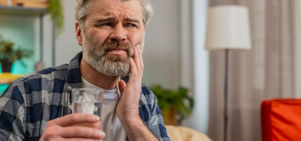 middle aged man holding his jaw in discomfort, TMJ pain