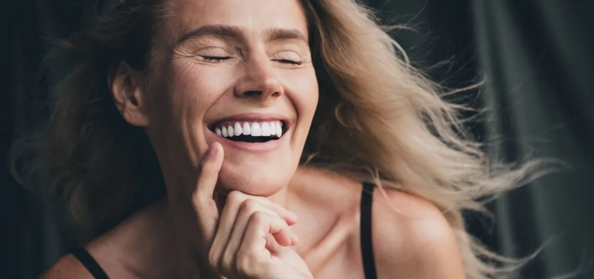 blonde woman smiling with eyes closed, perfect white smile