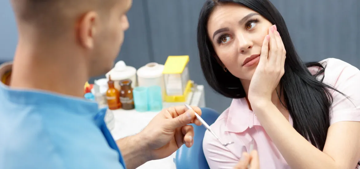 young woman talking to a dentist, severe tooth pain