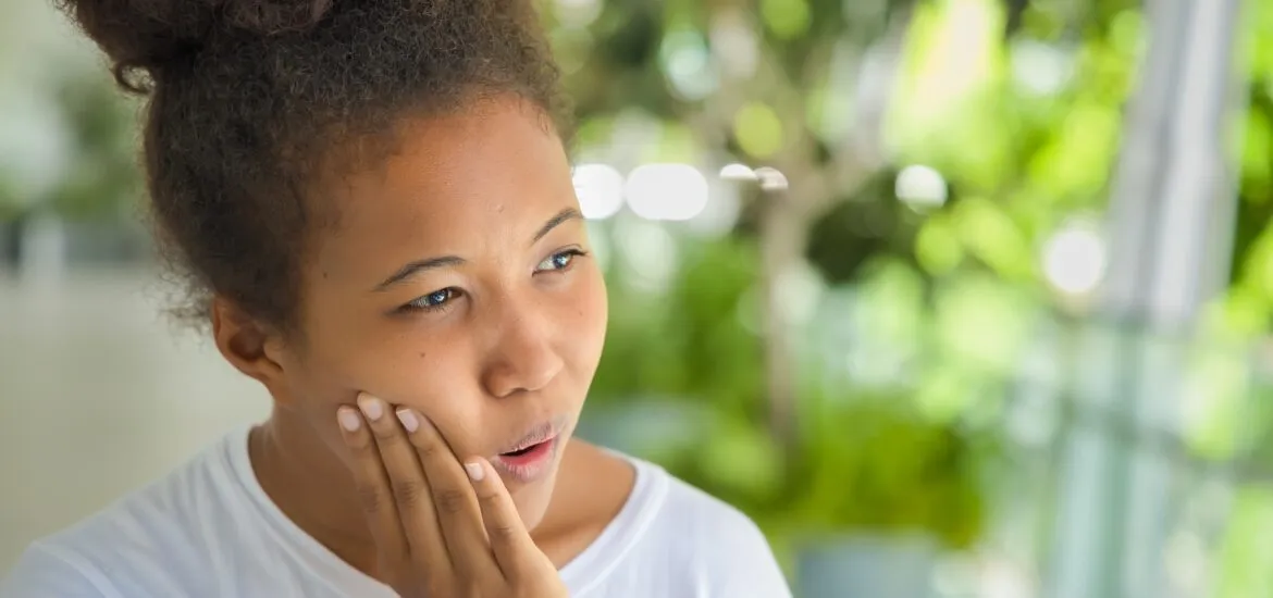 young woman suffering from severe tooth pain, hand on jaw