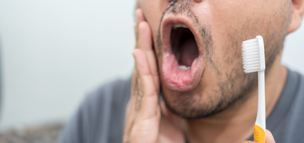closeup of a man touching his jaw in mirror, severe tooth pain