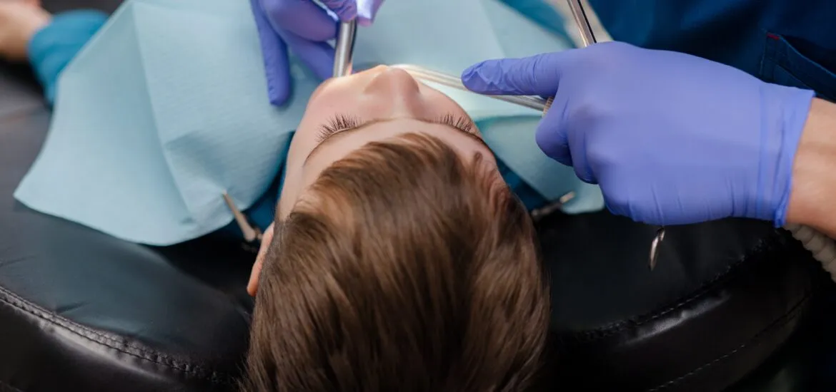 dentist examines the teeth of a child sitting in a dental chair